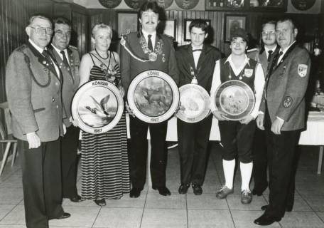 ARH Slg. Bartling 2294, Gruppe von Sportschützen (Männer und eine Frau) in einem Gasthaus stehend, präsentiert Königsscheiben 1987, Neustadt a. Rbge., 1987
