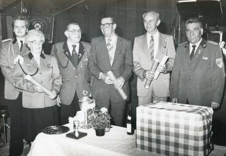 ARH Slg. Bartling 2297, Gruppe von fünf Schützen und einer Schützin, einige in Uniform, hinter einem Tisch stehend im Festzelt, Neustadt a. Rbge., um 1975