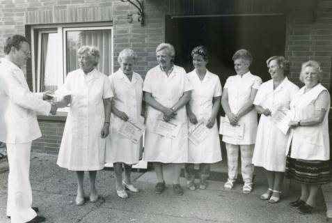 ARH Slg. Bartling 2341, Überreichung von Anerkennungsurkunden an sieben nebeneinander stehende Damen durch einen Herrn, DRK-Kreisverband, Neustadt a. Rbge., um 1975