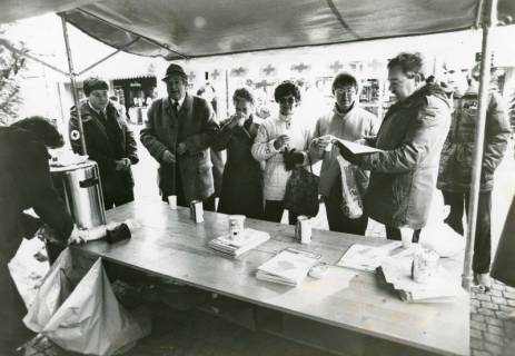 ARH Slg. Bartling 2346, DRK-Stand auf dem Weihnachtsmarkt in der Marktstraße vor der Sparkasse, Blick auf den Tisch mit Glühwein-Behälter, dahinter zahlreiche Kunden, Neustadt a. Rbge., um 1970