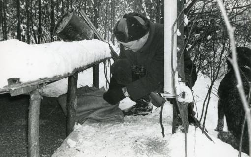 ARH Slg. Bartling 2481, Jagdpächter Dr. med. dent. Henning Gode mit Flinte, Fernglas und Hund bei hohem Schnee im winterlichen Wald bei der Wildfütterung knieend, Kreisjägerschaft, 1970