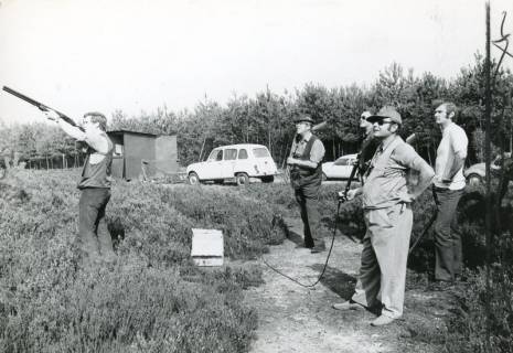 ARH Slg. Bartling 2492, Ein junger Tontaubenschütze auf dem Schießstand mit zum Schuss angelegter Flinte, hinter ihm vier zuschauende Kollegen, Kreisjägerschaft, Schneeren, 1973