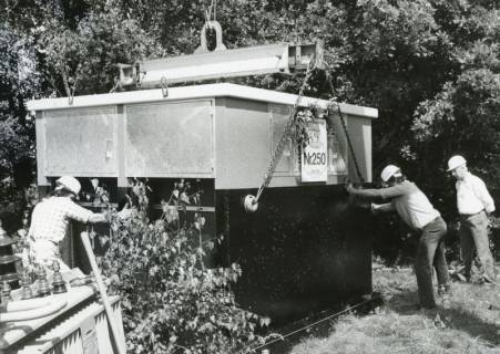 ARH Slg. Bartling 2503, Platzierung einer vorgefertigten Trafostation mit der (geschmückten) Nr. 250 mithilfe eines (hinter dem Fotografen stehenden) Krans, Neustadt a. Rbge., um 1975