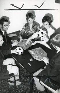 ARH Slg. Bartling 2512, Drei Männer und zwei Frauen um einen Tisch sitzend beim Zählen von Hartgeld, zwei Männer mit einem Ball in der Hand, Neustadt a. Rbge., 1973