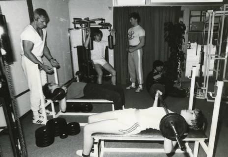 ARH Slg. Bartling 2575, Fitness-Studio, vier junge Männer an den Kraftgeräten und zwei Trainer, Neustadt a. Rbge., um 1975