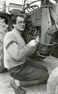 ARH Slg. Bartling 2583, Junger Monteur Heiko Thieß knieend neben dem Motorblock eines Treckers bei Reparaturarbeiten, Neustadt a. Rbge., um 1980