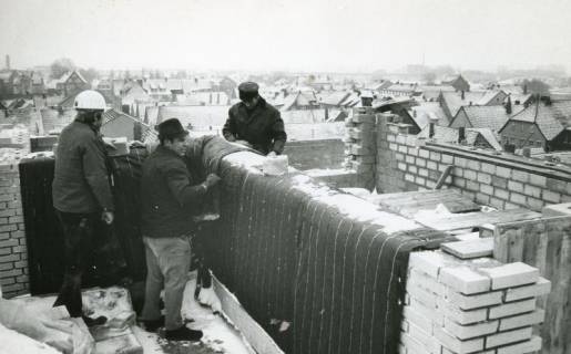 ARH Slg. Bartling 2691, Neubau der Kreissparkasse an der Marktstraße, Maurerarbeiten im Obergeschoss bei winterlichem Wetter mit Blick auf die leicht verschneiten Dächer der benachbarten Häuser, Neustadt a. Rbge., 1970