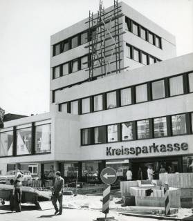 ARH Slg. Bartling 2700, Neubau der Kreissparkasse an der Marktstraße, Blick von der nördlichen Straßenseite auf die Pflasterarbeiten im Eingangsbereich des fast fertigen Gebäudekomplexes, Neustadt a. Rbge., 1972
