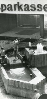 ARH Slg. Bartling 2701, Neubau der Kreissparkasse an der Marktstraße, Blick auf die Brunnenanlage mit spielenden Kindern vor dem in Arbeit befindlichen Eingangsbereich des Gebäudes, Neustadt a. Rbge., 1972