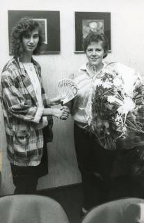 ARH Slg. Bartling 2792, Sparkassenangestellte Petra Hasselbring (l.) überreicht Irene Müller Geldscheine und einen Blumenstrauß in Folie, Neustadt a. Rbge., um 1975