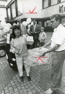 ARH Slg. Bartling 2798, Gewinnspiel auf dem Platz vor dem Eingang zur Kreissparkasse an der Marktstraße; junge Frau wirft eine Teilnahmekarte in einen Plastiksack, der von einem Mann offengehalten wird, Neustadt a. Rbge., um 1975