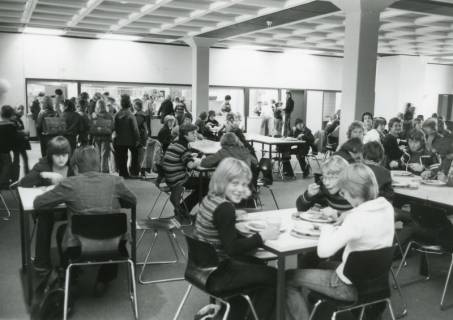 ARH Slg. Bartling 2863, Innenansicht der Kooperativen Gesamtschule (KGS), Mensa, Blick auf die an den Tischen sitzenden und essenden Schüler*innen, Neustadt a. Rbge., um 1975