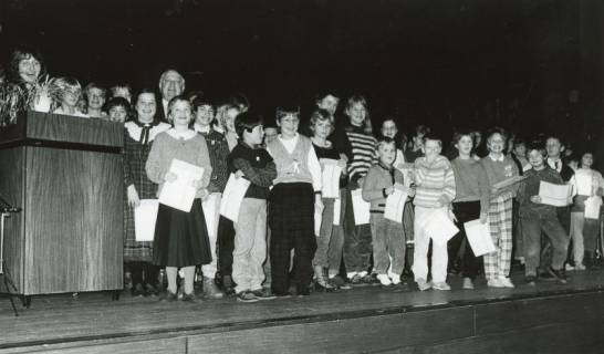 ARH Slg. Bartling 2892, Zahlreiche Grundschulkinder auf einer Bühne stehend mit einer Urkunde in der Hand, hinter den Kindern Bürgermeister Henry Hahn, Neustadt a. Rbge., vor 1974