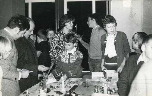ARH Slg. Bartling 2928, Gymnasium an der Gaußstraße, Weihnachtsbasar, Tisch mit ausgebreiteten Angeboten, dahinter Schüler und Erwachsene, Neustadt a. Rbge., 1969