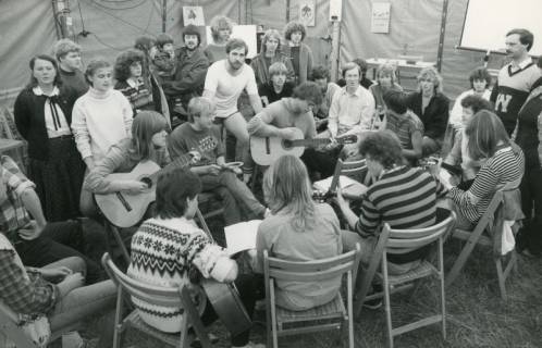 ARH Slg. Bartling 2986, Junge Leute bei einer Tagung in einem Zelt in lockerer Runde beim Singen in Begleitung von zwei Gitarren, Mardorf, 1984