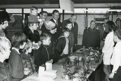 ARH Slg. Bartling 2996, Sonderschule, Weihnachtsbasar mit Ausstellung und Verkauf von Werken, die von Schüler*innen geschaffen wurden, Blick auf den Tisch und die Interessenten, Neustadt a. Rbge., 1970