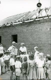 ARH Slg. Bartling 3059, Richtfest des Rohbaus eines neuen Kindergarten, davor einige Kinder samt älterem Akkordeonspieler, Neustadt a. Rbge., um 1970