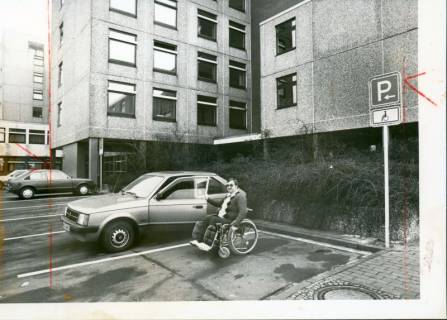 ARH Slg. Bartling 3156, Kreiskrankenhaus (später: KRH Klinikum Neustadt a. Rbge.), Lindenstraße 75: Rollstuhlfahrer neben seinem PKW, Neustadt a. Rbge., um 1975