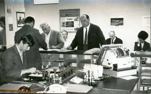 ARH Slg. Bartling 3182, Kundenverkehr in der Kfz-Zulassungsstelle, Blick über den Schreibtisch eines Beamten und den Tresen auf die Kunden, Neustadt a. Rbge., 1970