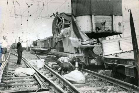 ARH Slg. Bartling 3188, Entgleisung eines Güterzugs im Bereich des Bahnhof Wunstorf, Versuch zur Behebung des Schadens durch zwei Arbeiter, Blick am Zug entlang, Wunstorf, 1970
