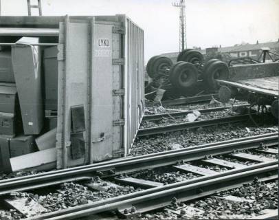 ARH Slg. Bartling 3189, Entgleisung eines Güterzugs im Bereich des Bahnhof Wunstorf, Blick auf einen quer zu den Gleisen liegenden Container und auf zwei umgestürzte LKW-Achsen, im Hintergrund das Gebäude der Firma Nolte, Wunstorf, 1970