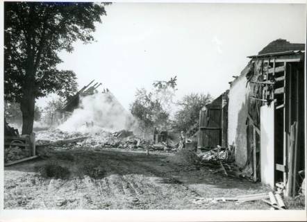 ARH Slg. Bartling 3259, Qualmende Trümmer eines abgebrannten Hauses auf einem Hof, um 1974