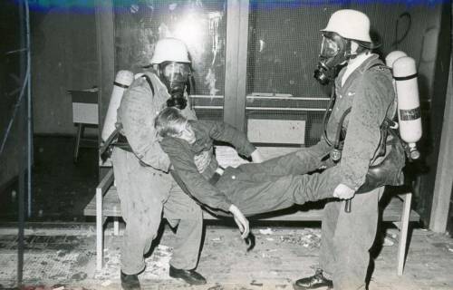 ARH Slg. Bartling 3266, Bergung eines bewusstlosen Opfers durch zwei Feuerwehrleute mit Atemschutz-Vollgesichtsmaske und Sauerstoffflaschen, Übung vor einem Eingang zum FZZ, Neustadt a. Rbge., 1974