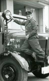 ARH Slg. Bartling 3299, Werner Hinz, Mitglied der Feuerwehr in Arbeitsuniform beim Pflegedienst am Scheinwerfer eines Löschfahrzeugs, Ansicht von vorn, Neustadt a. Rbge., 1969