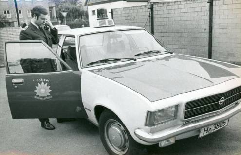ARH Slg. Bartling 3362, Dienstfahrzeug der Neustädter Polizei, Polizeimeister Diekmann stehend und telefonierend vor der geöffneten Beifahrertür des neuen Opel-Rekord (Kennzeichen: H-3885), Neustadt a. Rbge., 1974