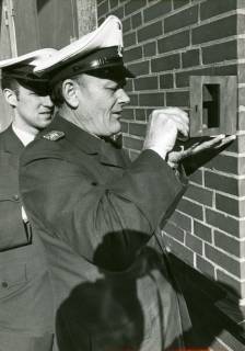 ARH Slg. Bartling 3371, Aufschließung eines an einer Gebäudeecke angebrachten Schlüsselkastens durch den Polizeioberkommissar Haase, hinter ihm der junge Polizist Kaiser, Neustadt a. Rbge., 1972