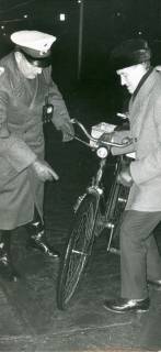 ARH Slg. Bartling 3432, Polizist in der Dunkelheit bei der Kontrolle der Beleuchtung des Fahrrades eines älteren Herrn, Neustadt a. Rbge., 1969