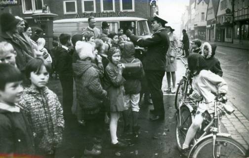 ARH Slg. Bartling 3433, Polizeimeister Franz Baumann unterrichtet eine Gruppe von Schulkindern mit Eltern auf dem Kirchplatz vor der Redeker'schen Rats-Apotheke (Schulstraße 1), Neustadt a. Rbge., 1969