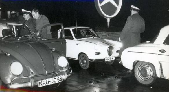 ARH Slg. Bartling 3434, Zwei Polizisten im Dunkeln vor einer Mercedes-Werkstatt bei der Beleuchtungskontrolle der Fahrzeuge (VW-Käfer und Goggomobil TS 250 Coupé), Neustadt a. Rbge., 1969