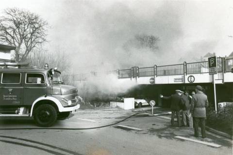 ARH Slg. Bartling 3437, Polizisten vor der Einfahrt zur Parkpalette, durch die dichter, weißer Rauch quillt; links ein Löschfahrzeug der Feuerwehr, Neustadt a. Rbge., um 1975