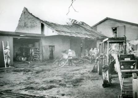 ARH Slg. Bartling 3446, Löscheinsatz beim Brand einer Remise mit aus dem Dach aufsteigendem Rauch, rechts vor dem Gebäude zwei verbannte Frontlader, Neustadt a. Rbge., um 1975