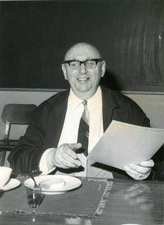 ARH Slg. Bartling 3455, Kantor Fritz Meinecken vor einer Tafel am Kaffeetisch mit einer Umlaufmappe in der Hand sitzend, Neustadt a. Rbge., um 1975