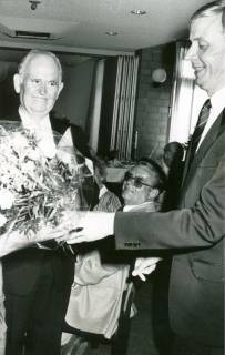 ARH Slg. Bartling 3457, Übereichung eines Blumenstraußes an Pastor Helmut Niemeyer (?) durch Superintendent Hans Dietrich Tjarks (v. l.) beide in Zivil sich gegenüberstehend, Neustadt a. Rbge., um 1985