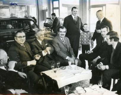 ARH Slg. Bartling 3561, Kleine Feier in der Werkhalle der Firma Valentin Reichardt, sechs Herren an einem Tischchen vor den Autos mit einem Glas Sekt und einer Zigarre sitzend, Neustadt a. Rbge., 1972