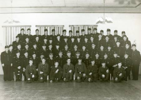 ARH Slg. Bartling 3631, Gruppenbild der Mitglieder der Freiwilligen Feuerwehr Neustadt a. Rbge. in Uniform (mit Mütze) aufgestellt in einem Saal, Ansicht von vorn, Neustadt a. Rbge., um 1980