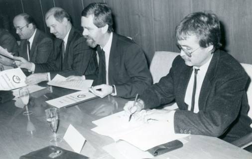 ARH Slg. Bartling 3673, Vier Männer hinter einem Tisch bei der Unterschrift unter einen Vertrag über die Verkehrsgemeinschaft mit dem Landkreis Nienburg, Neustadt a. Rbge., um 1985