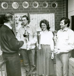 ARH Slg. Bartling 3710, Überreichung von Pokalen an zwei Amedorfer Schützen und eine Schützin durch N. N., an der Wand im Hintergrund sechs Preisteller, Amedorf, um 1980