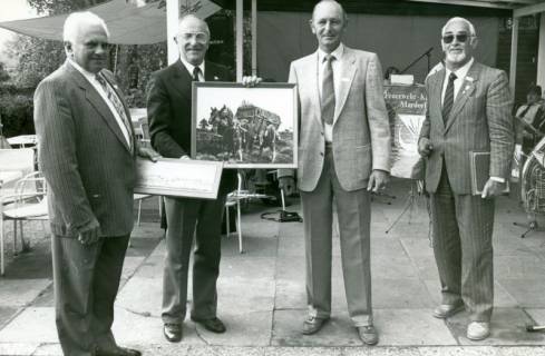 ARH Slg. Bartling 3717, Vier ältere Herren nebeneinander stehend auf der Terrasse eines Lokals, drei Herren mit historischen Bildern in der Hand, Mardorf, um 1980