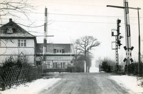 ARH Slg. Bartling 3798, Beschrankter Bahnübergang am Fritz-Blume-Weg, leicht verschneit, Blick auf das Gebäude der Post, Poggenhagen, 1972