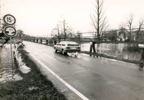 ARH Slg. Bartling 3882, Hochwasser der Leine, Blick auf einen PKW, der über die kurz vor der Überschwemmung stehende Straße Am Fährhaus (mit begleitendem Fußgängersteg) Richtung Bordenau fährt, 1987