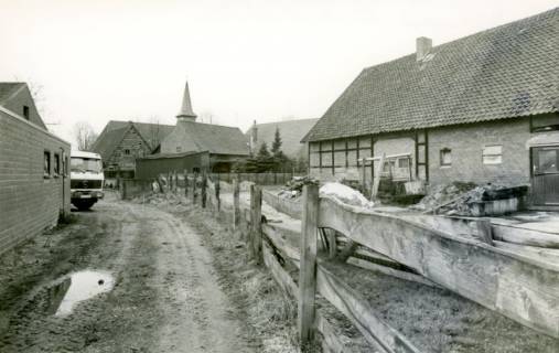 ARH Slg. Bartling 3920, Blick über einen Nebenweg und das Nebengebäude eines Bauernhofs auf den Kirchturm der Dorfkirche, Alt-Bordenau, um 1985
