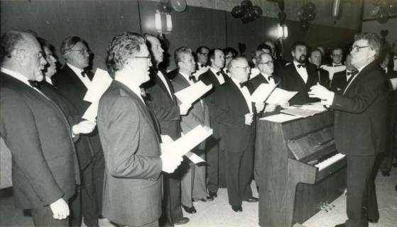 ARH Slg. Bartling 3939, Männergesangverein Bordenau, Auftritt in einem geschmückten Saal unter dem Dirigat von Gerhard Bruns vor einem geöffneten Klavier, Bordenau, um 1980