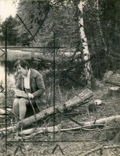 ARH Slg. Bartling 4030, Die Esperker Lehrerin und Naturschützerin Maria Draheim auf einem Baumstamm sitzend mit einem Papier auf dem Schoß am Ufer des Heideweihers im Blanken Flat, Esperke-Warmeloh, 1970