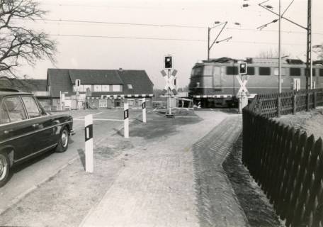 ARH Slg. Bartling 4042, Bahnübergang an der Eilveser Hauptstraße, Blick vom Fahrradweg in Richtung Osten auf die geschlossene Schranke und die kreuzende E-Lokomotive, Eilvese, um 1980