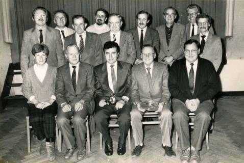 ARH Slg. Bartling 4133, Gruppenfoto der Gemeinderatsmitglieder (?), 13 Männer und 1 Frau, sitzend und stehend vor einem Bühnenvorhang, Empede, um 1980