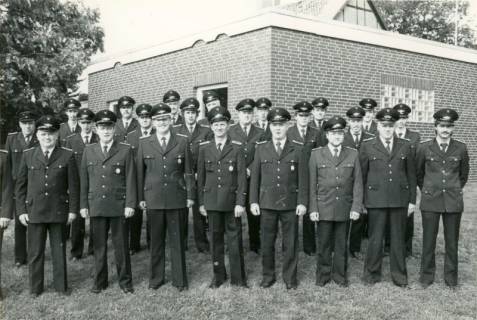 ARH Slg. Bartling 4143, Gruppenfoto der Feuerwehrleute in Ausgehuniform auf dem Rasen hinter dem Gebäude, Empede, 1985